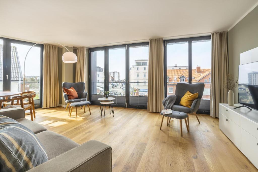 a living room with a couch and chairs and windows at InselLoft Wohnung 6 in Borkum
