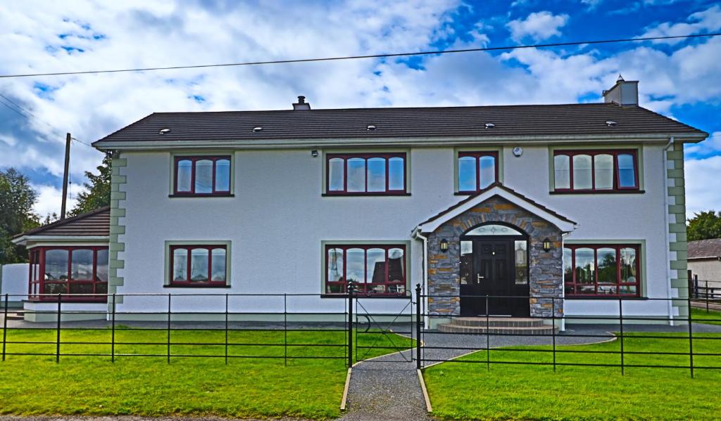 a large white house with a black roof at Mossvale Lodge Country House Bed and Breakfast in Antrim