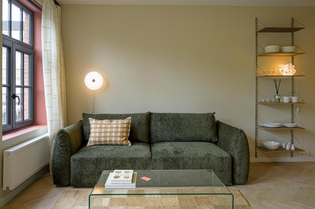 - un salon avec un canapé vert et une table en verre dans l'établissement SHWAY - The Book Binder, à Anvers