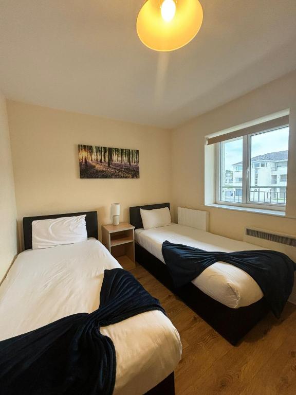two beds in a room with a window at Four Bedroom Apartment Athlone in Creggan