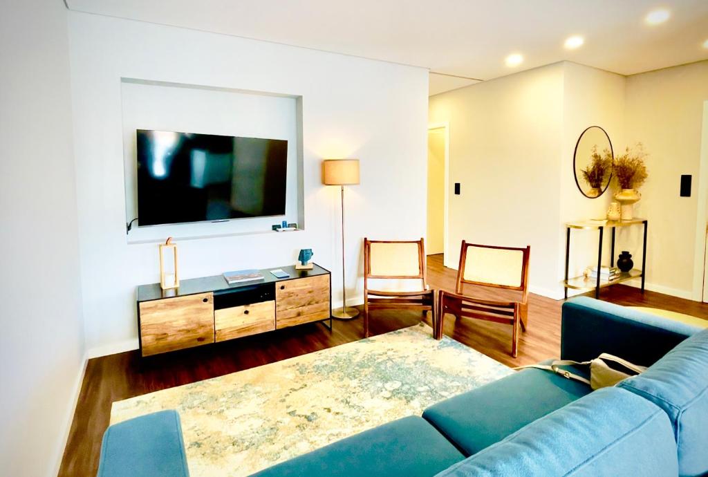 Una sala de estar con un sofá azul y un televisor en NearTheSEA by YoursPorto, en Matosinhos