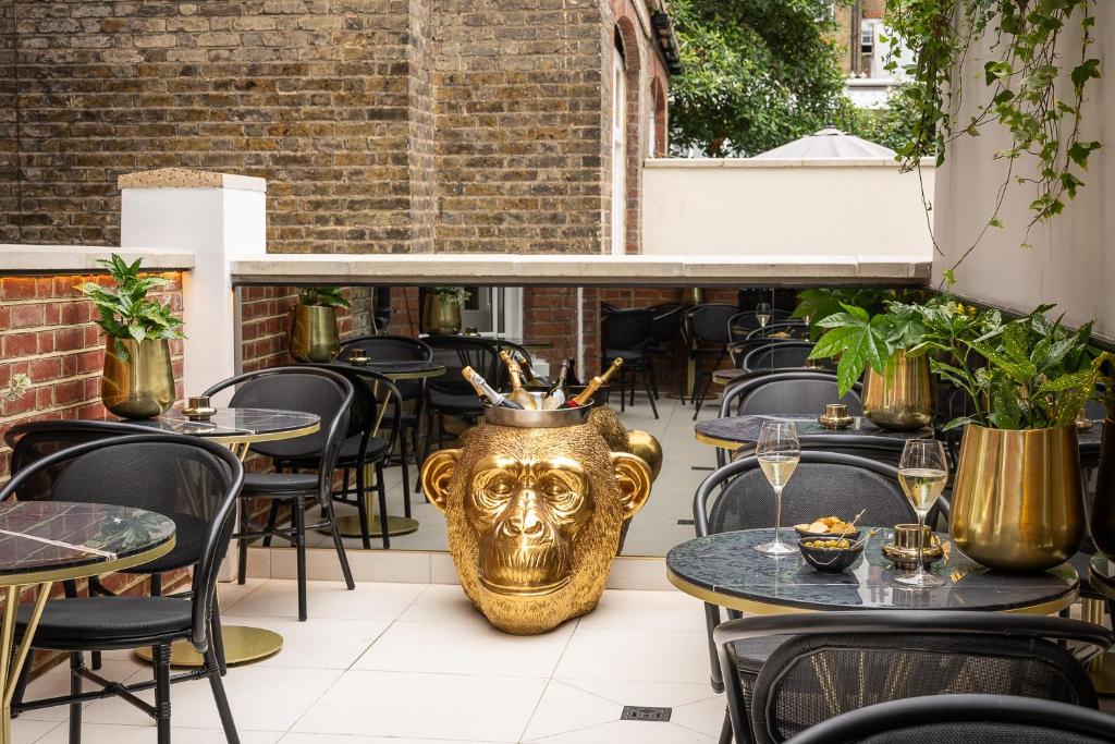 een restaurant met tafels en een gouden leeuwenkop op de vloer bij Ellen Kensington in Londen