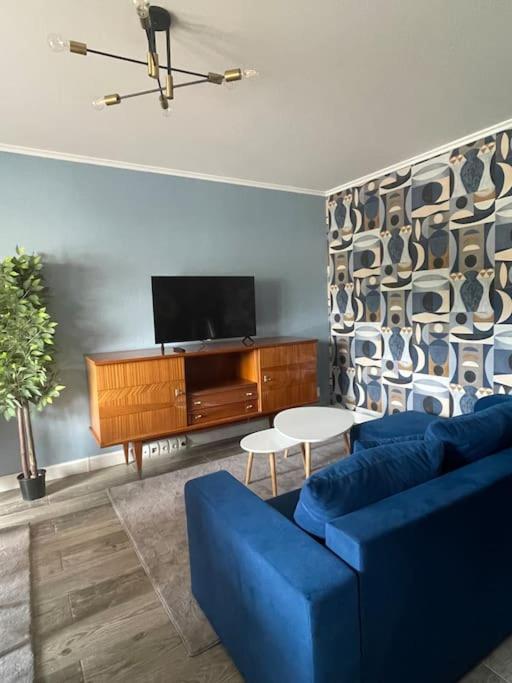 un salon avec un canapé bleu et une télévision dans l'établissement Charming and Cosy Apartment near Paris, à Houilles