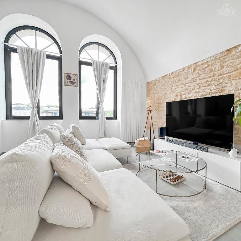 un salon blanc avec un canapé blanc et une télévision dans l'établissement Loft Lumineux Proche de la Cathédrale, à Metz