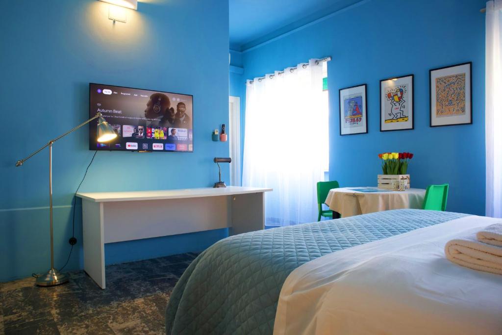 a blue room with a bed and a desk and a tv at Apartment Sonnino 37 in Cagliari