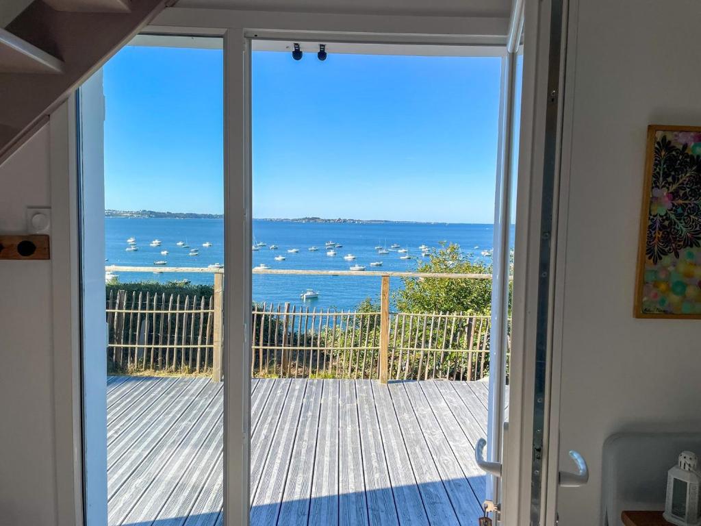 a door to a balcony with a view of the ocean at Ty Lazo: Sérénité en bord de mer, havre de paix. in Plouézec