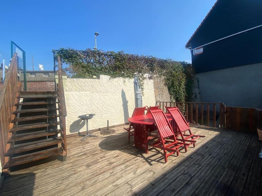 une table et des chaises rouges sur une terrasse en bois dans l'établissement Les embruns - Mer - dog friendly, à Ault