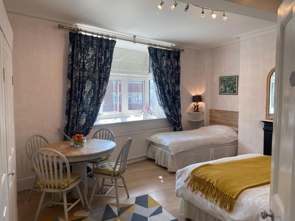 a bedroom with two beds and a table and a window at Deluxe Three Bed BnB in Henley-on-Thames near Station River & Town Centre in Henley on Thames