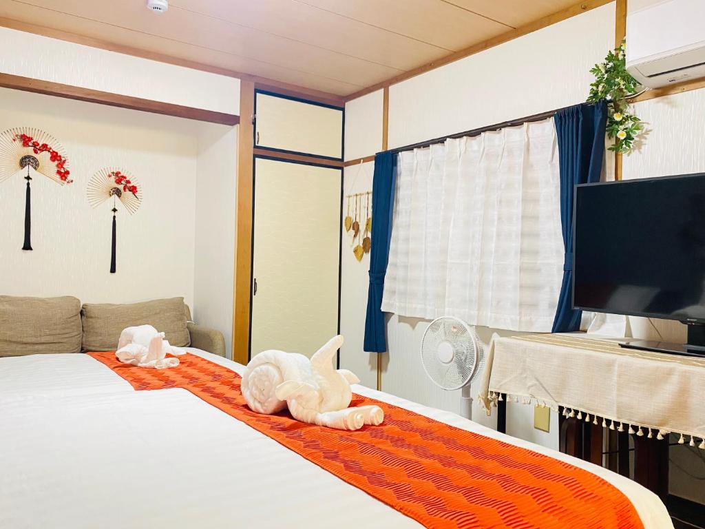大阪大阪梅田淀川花民宿家庭房b套的卧室里有一张床，橙色地毯上放着两只毛绒玩具