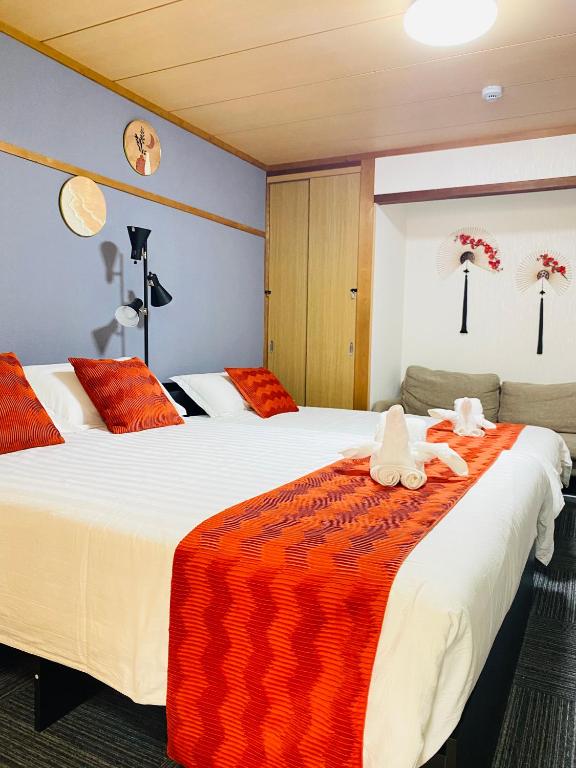 two beds in a room with red and white sheets at Umeda Yodogawa Cozy Home B 步行5分钟到JR站 直达京都神户 Umeda 1站 新大阪2站 in Osaka