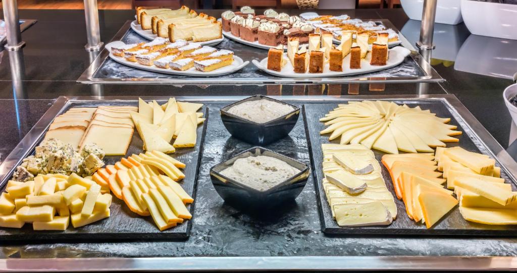 a buffet line with cheese and other foods on trays at H10 Ocean Suites in Corralejo