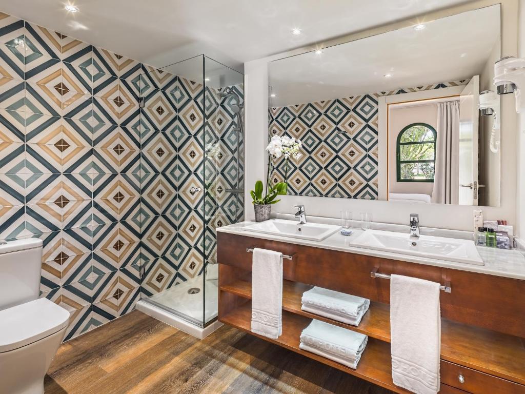 a bathroom with a tub and a sink and a mirror at H10 Ocean Suites in Corralejo