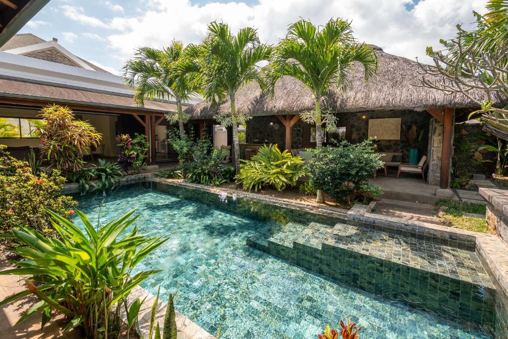 a swimming pool in front of a house with palm trees at Villa Paradis in Grand Baie