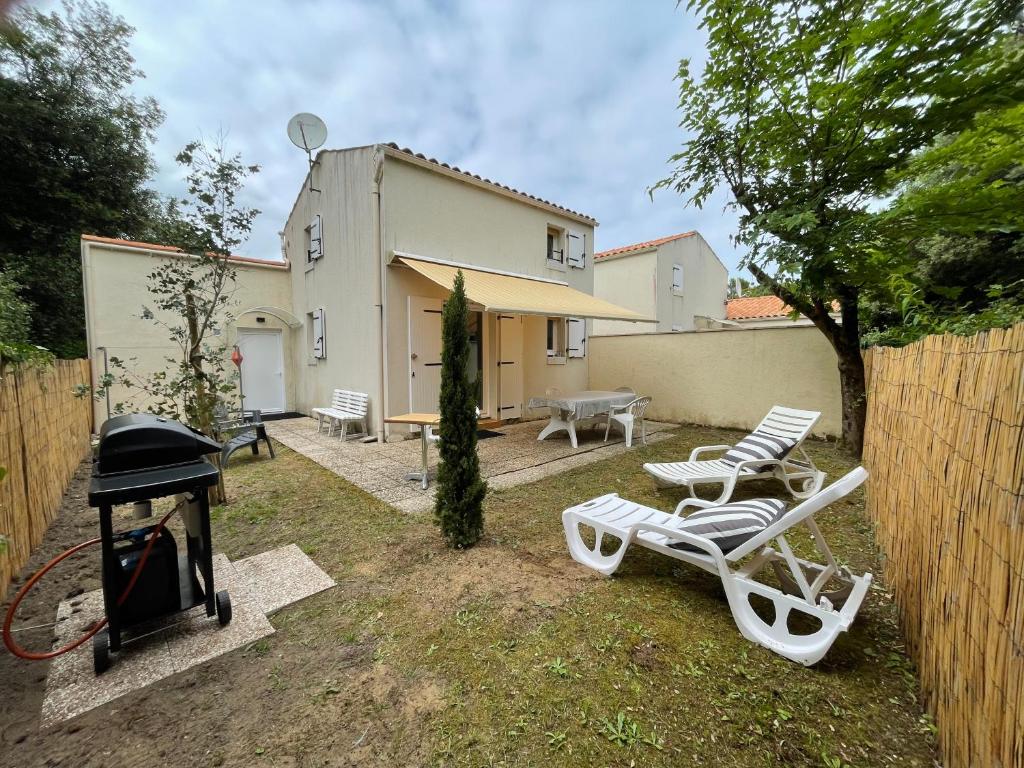 une arrière-cour avec des chaises longues, un barbecue et une maison dans l'établissement Havre de paix, à Les Sables Vignier