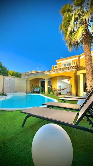 une maison avec un palmier, une table et des chaises dans l'établissement La villa Soleil, à Fourques