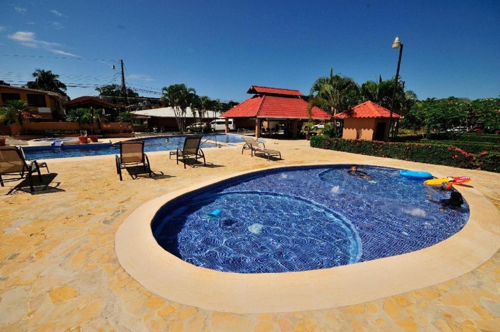 a large plunge pool in a resort with chairs at In the HEART of Jaco at Villas Paraiso in Jacó