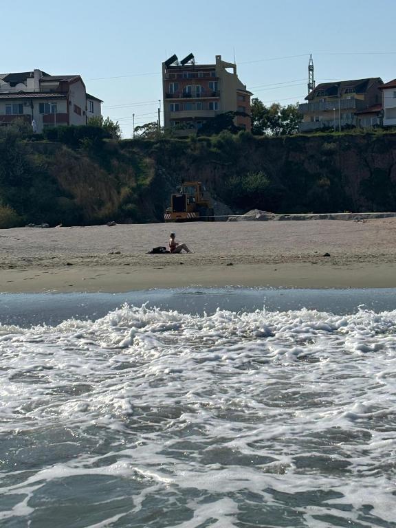a man sitting on a beach near the water at Vila Ilinca in Agigea