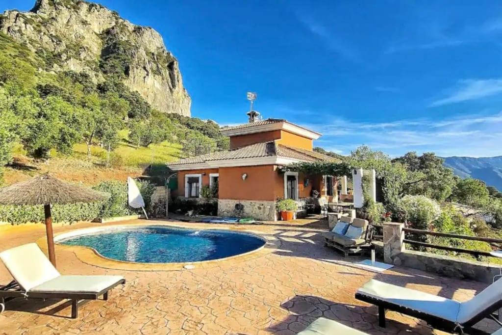 a house with a swimming pool in front of a mountain at Casa La Roca in El Gastor