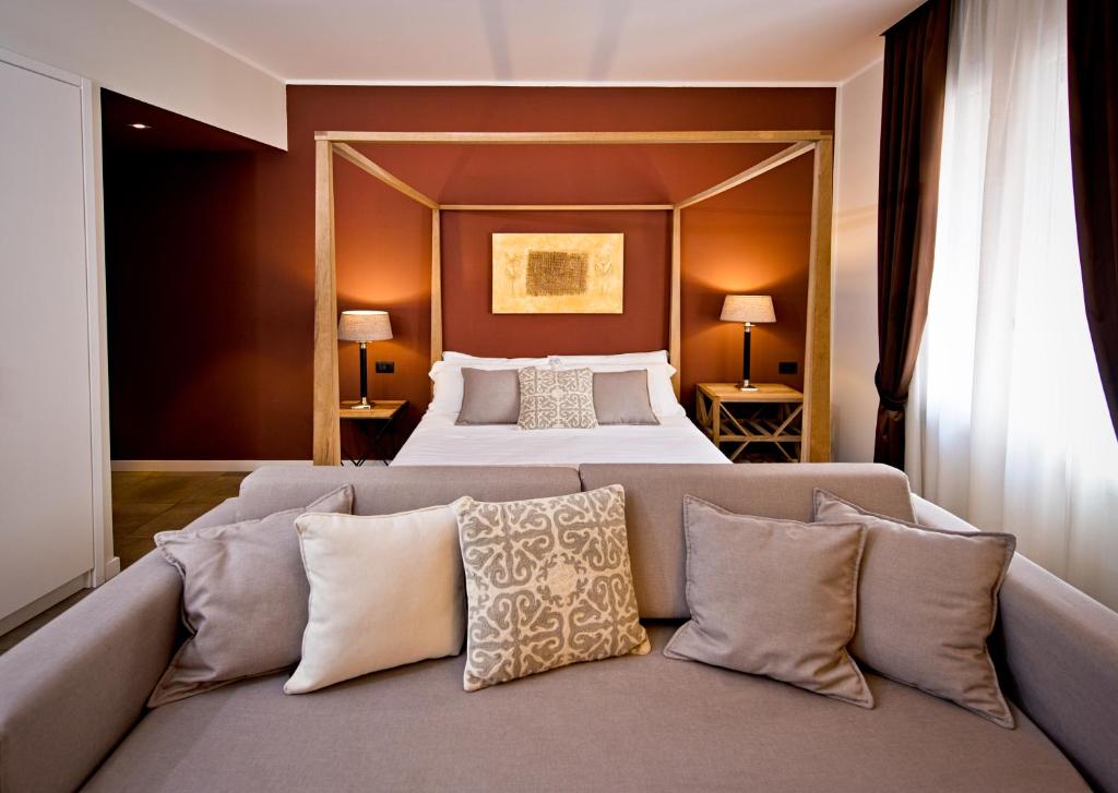 a bedroom with a bed and a couch with pillows at Delle Vittorie Luxury Rooms&Suites in Palermo