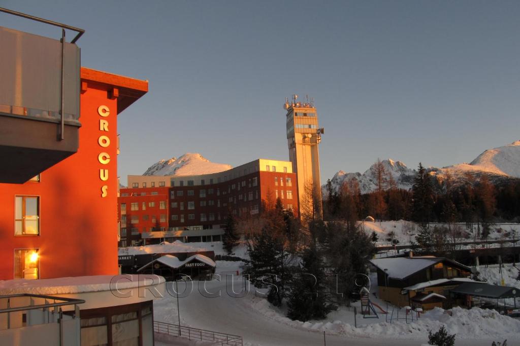 un edificio con una torre de reloj en la nieve en Apartmán Štrbské Pleso - Crocus 219, en Štrbské Pleso