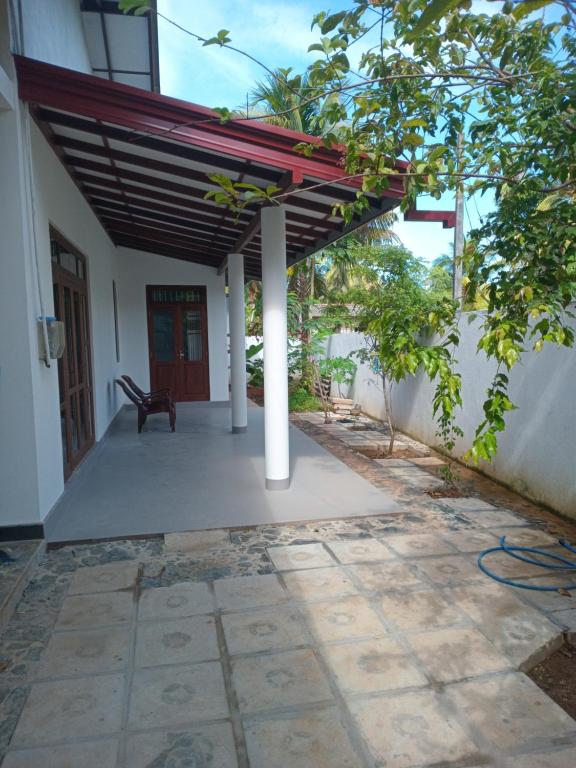 un patio con tenda da sole e una panchina su un edificio di Mihinsa Guest a Kosgoda