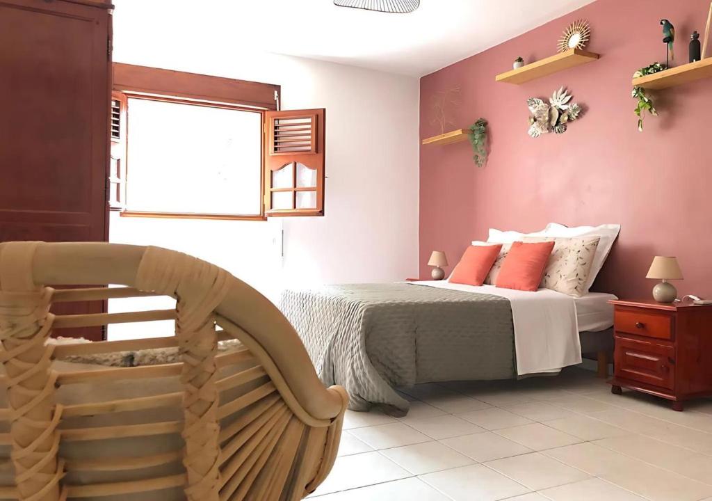Un dormitorio con una cama con paredes rosas y una silla en La Suite Sapotille, en Trois-Rivières
