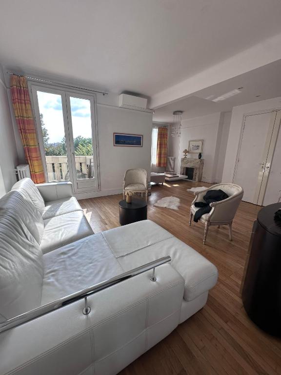 une chambre avec un grand lit blanc et un salon dans l'établissement Luxueux appartement à la Porte d'Auteuil - 16ème Arrondissement, à Paris