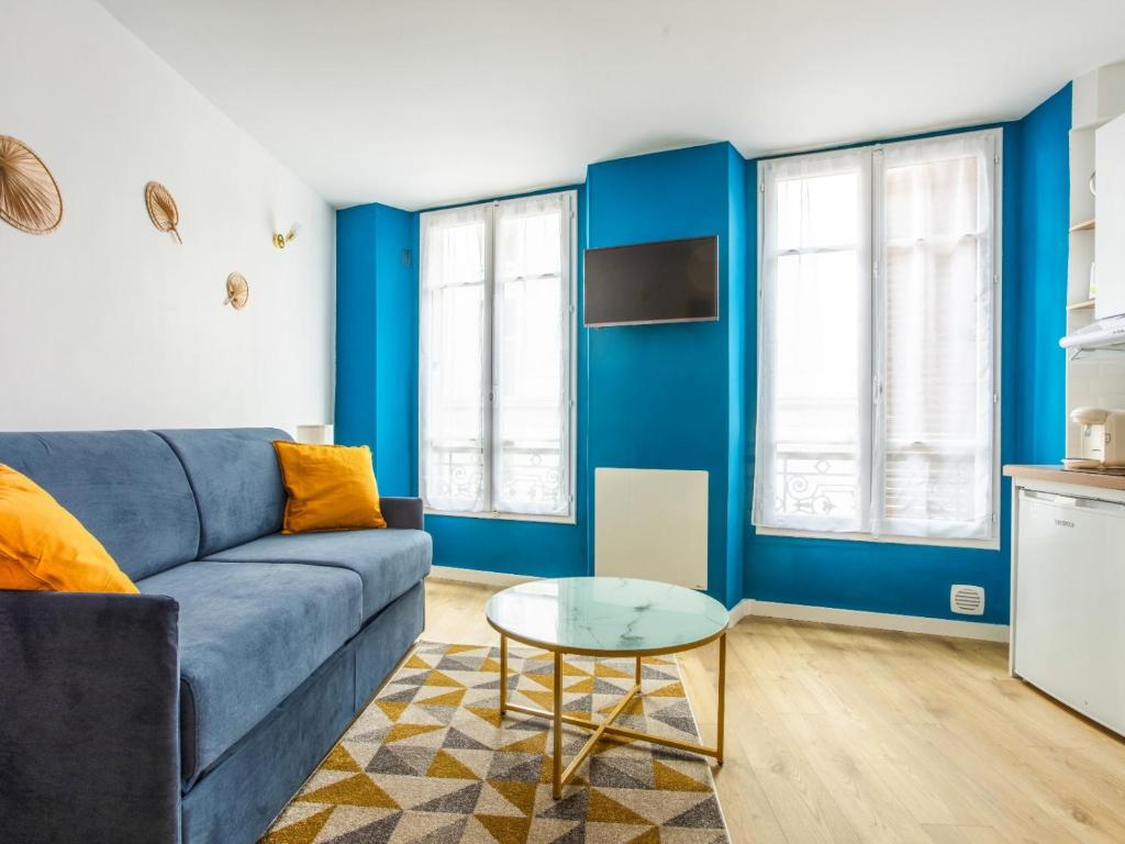 - un salon avec des murs bleus et un canapé bleu dans l'établissement Le Cessac - Versailles, à Versailles