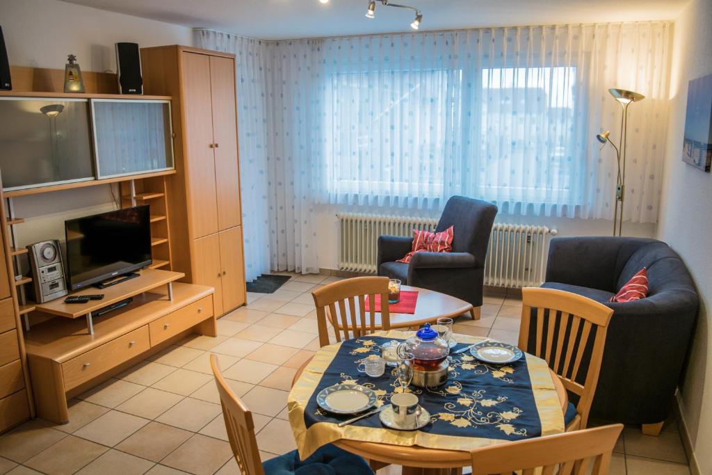 ein Wohnzimmer mit einem Tisch, Stühlen und einem TV in der Unterkunft Ferienwohnung Bäumer Borkum - Nichtraucher & allergikerfreundlich in Borkum