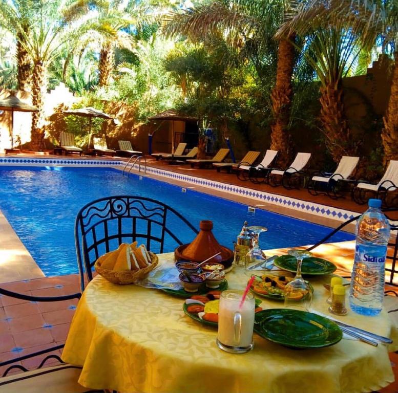 a table with food on it next to a swimming pool at Riad le Petit Jardin in Zagora