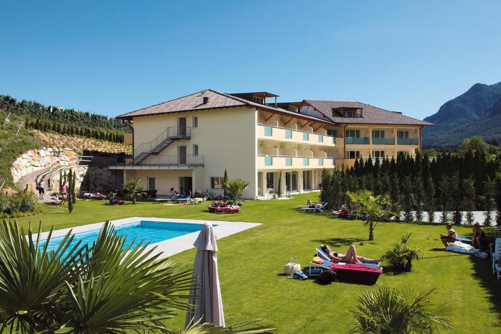 um resort com pessoas deitadas na relva ao lado de uma piscina em Hotel Weingarten em Caldaro