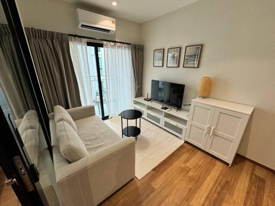 a living room with a couch and a television at Super Naiyang Title 1Bdr 600m to beach in Nai Yang Beach