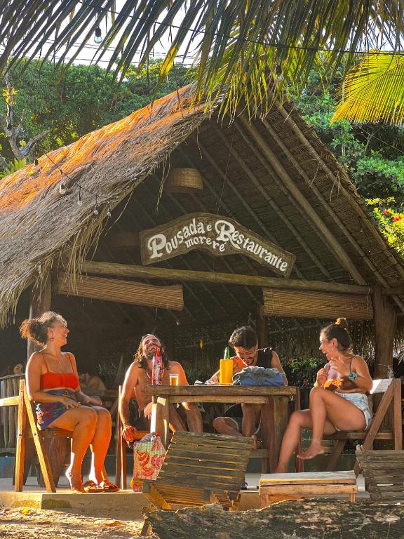 a group of people sitting at a table on the beach at Pousada Moreré in Ilha de Boipeba