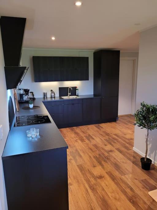 a kitchen with black cabinets and a wooden floor at Romslig leilighet midt i Lofoten in Leknes
