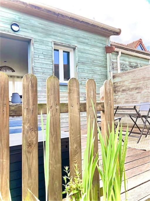 une clôture en bois devant une maison dans l'établissement Maison bord de mer avec terrasse - Riva Bella, à Ouistreham