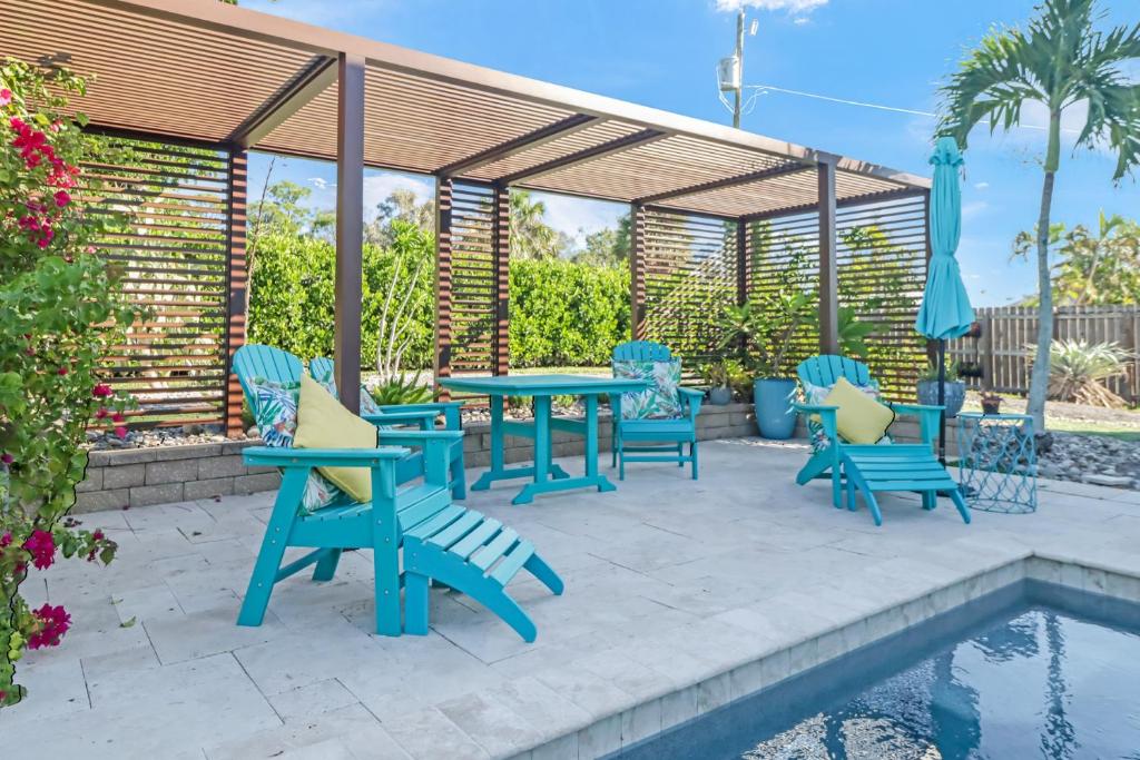 a patio with a table and chairs next to a pool at Coastal Soul House in the heart of Naples in Naples