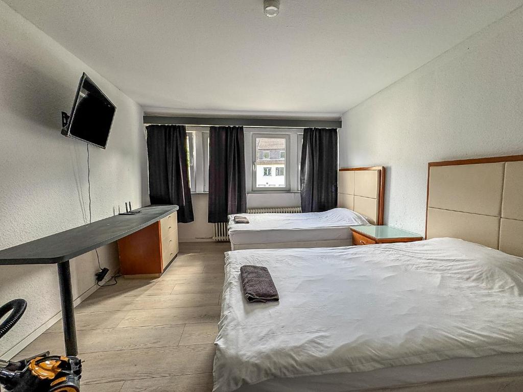 a hotel room with two beds and a television at Cici Monteurunterkünfte in Werdohl mit Küche, WLAN, TV, Parken in Werdohl