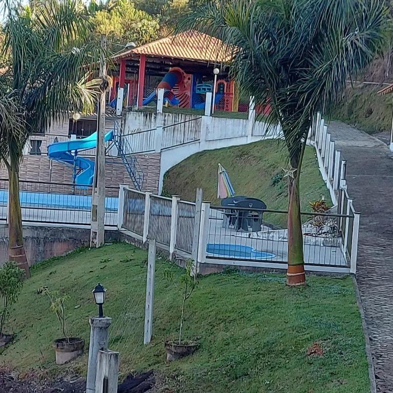a white fence with a playground in the background at Rancho das Montanhas in Muniz Freire