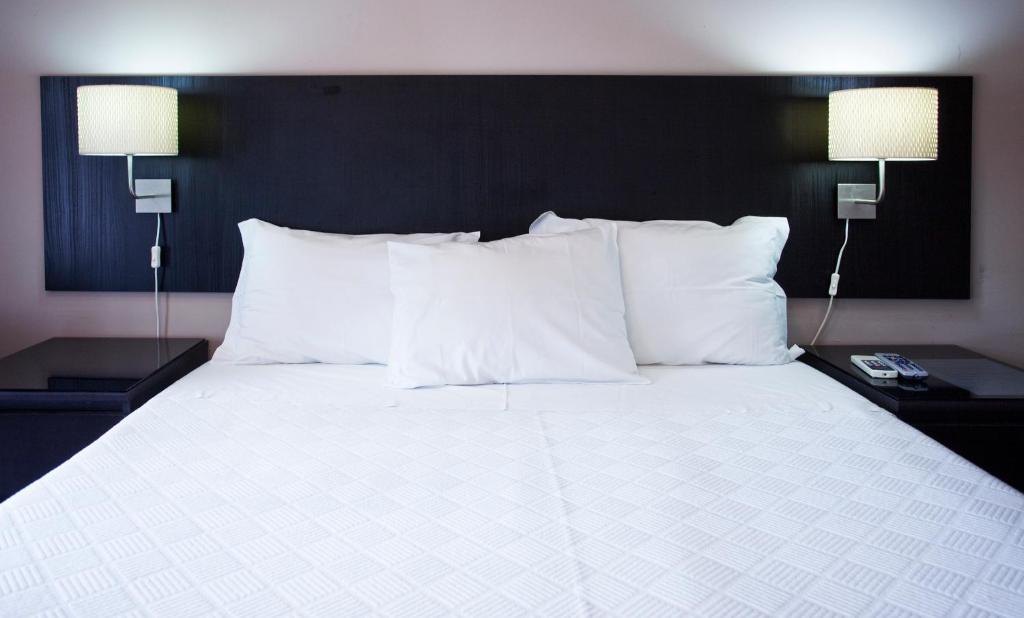 a large bed with white pillows and two lamps at Residencial Principe Guest House in Barreiro