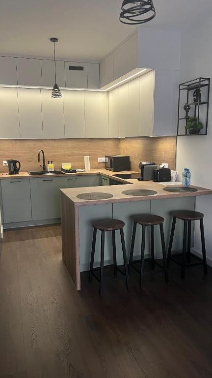 a kitchen with three bar stools and a counter at Apartament Rytm - Metro Kabaty in Warsaw