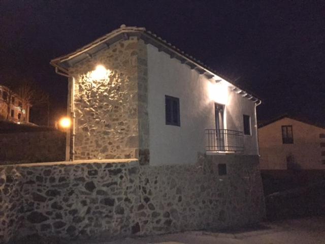 un edificio de piedra con dos luces encendidas por la noche en La Casita Del Castañar, en Béjar