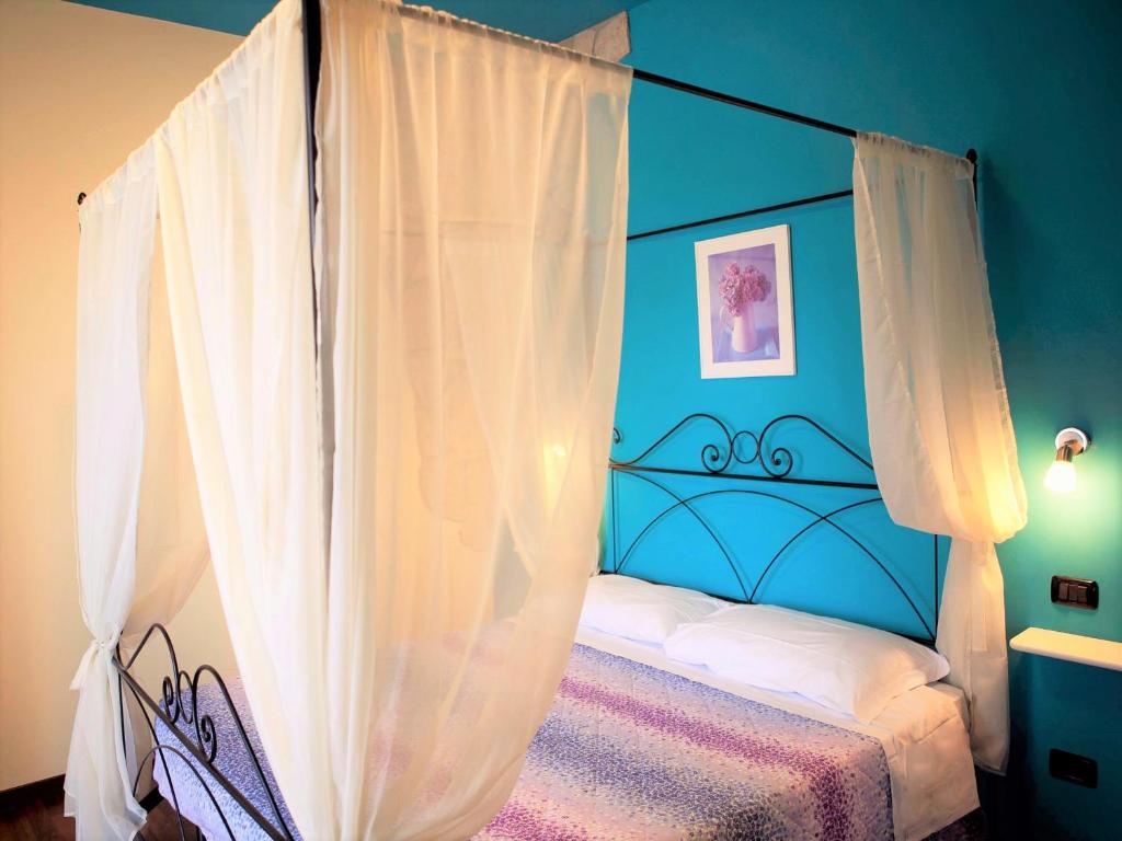 アッシジにあるB&B Raffioriの青いベッドルーム(白いカーテン付きの天蓋付きベッド付)