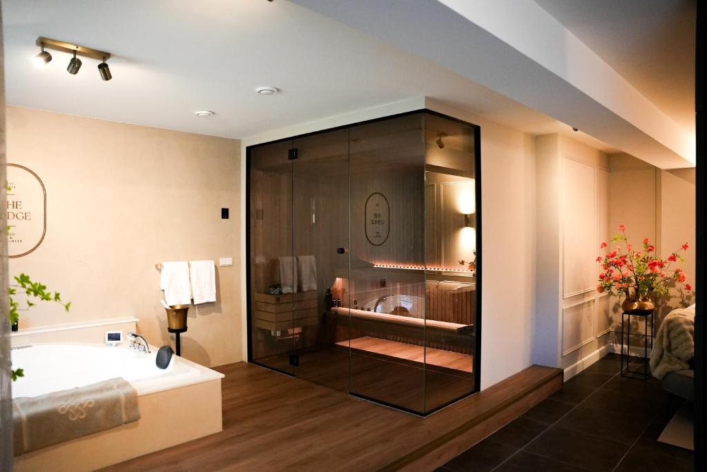 a bathroom with a bath tub and a sink at The Lodge Bed & Wellness Oisterwijk Sauna, Jacuzzi, Luxury in Moergestel
