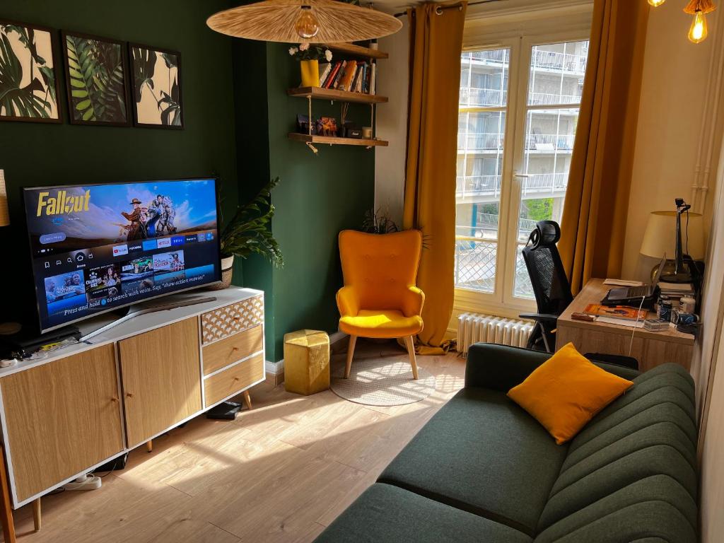 un salon avec un canapé et une télévision à écran plat dans l'établissement Un charmant appartement à côté de la cité florale, à Paris