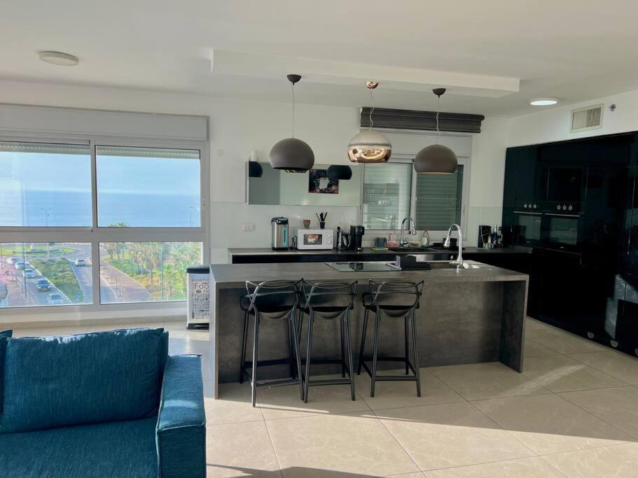 a kitchen with a counter with bar stools in it at Prince Palace Netanya Lagoon Beach 3BR in Netanya