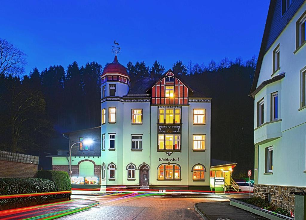 ein großes Gebäude mit einem Turm darüber in der Unterkunft Hotel Weidenhof in Plettenberg