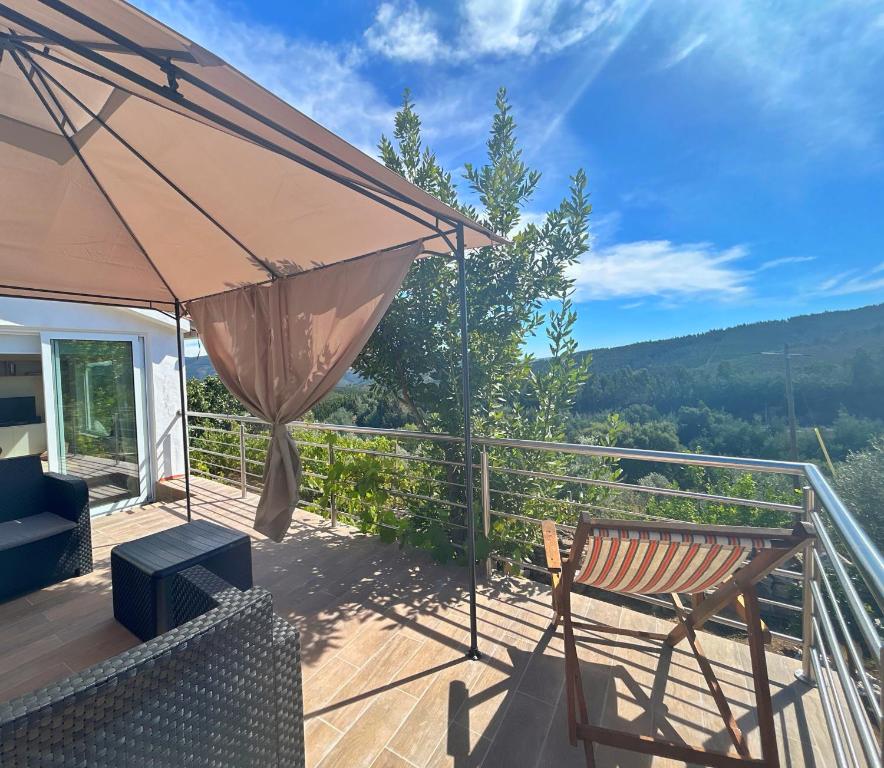 una terraza de madera con un banco y una sombrilla en Casa do Beco, en Moninho