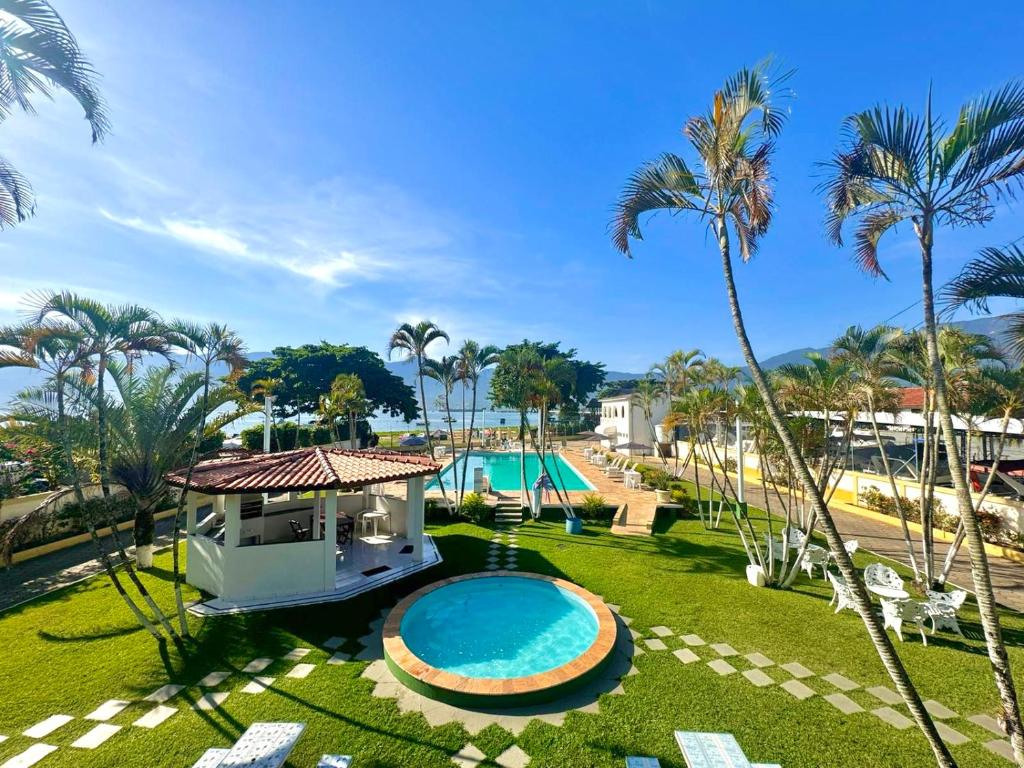 un complejo con piscina y palmeras en Hotel Recanto dos Pássaros, en São Sebastião