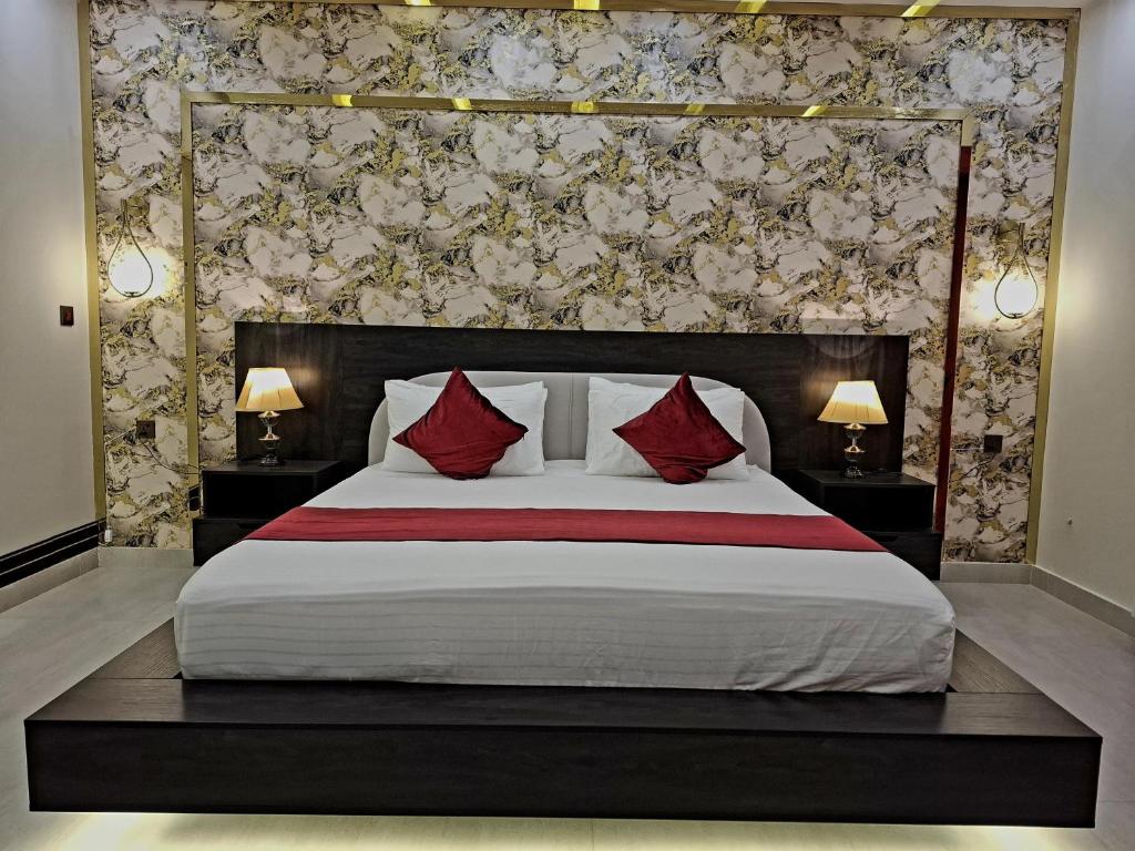 a bedroom with a large bed with red pillows at Royal Galaxy Hotel & Residence - Near Islamabad International Airport & Motorway in Islamabad
