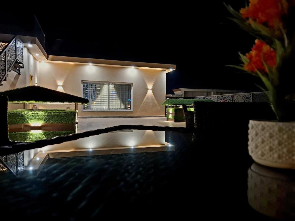 a house lit up at night with a swimming pool at Royal Galaxy Hotel & Residence - Near Islamabad International Airport & Motorway in Islamabad